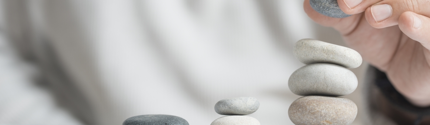 Man stacking pebbles on table